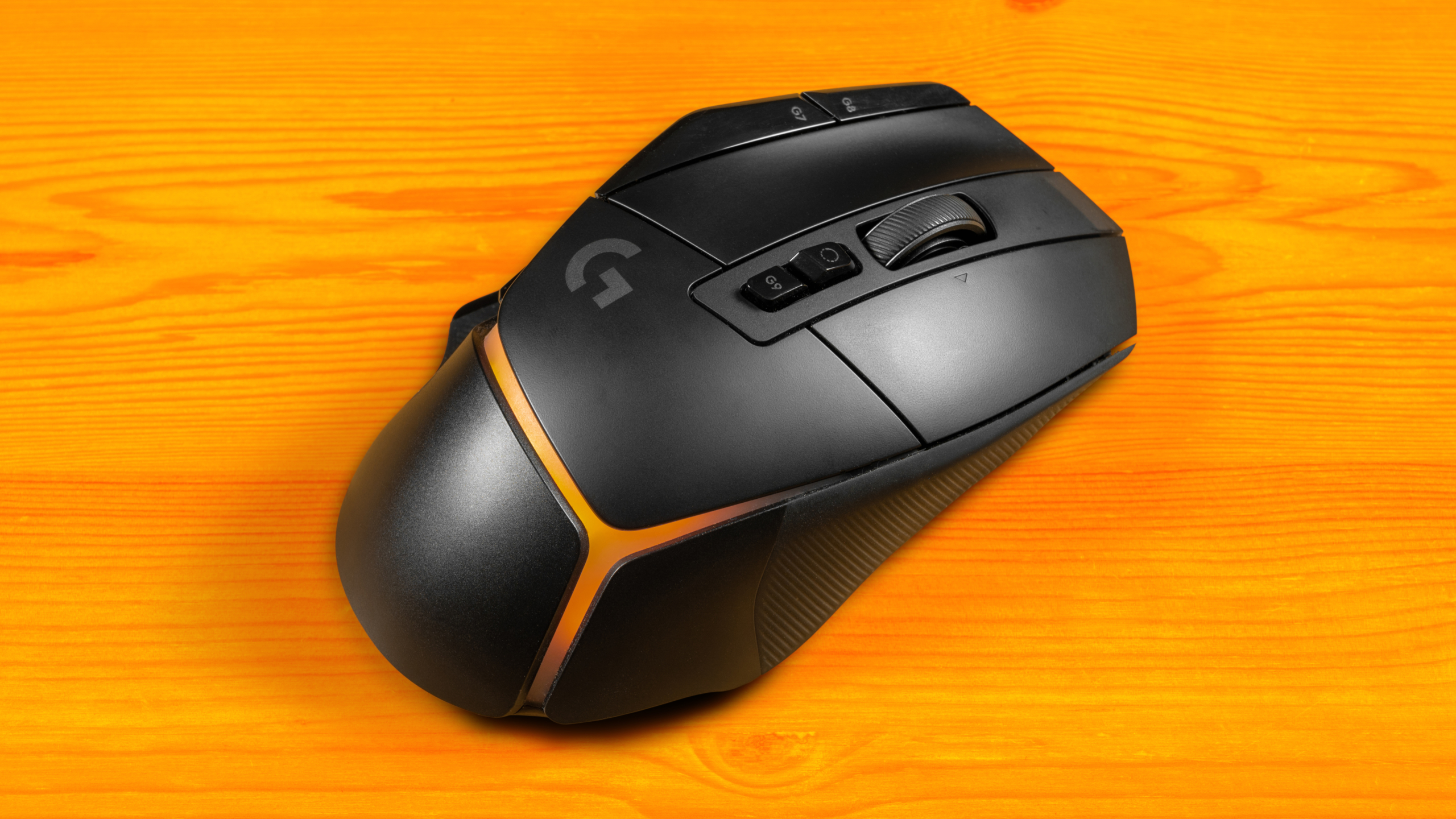 Bovenaanzicht van een Logitech G502 X Plus-muis, met de RGB-verlichting ingesteld op een oranje kleurenverloop.