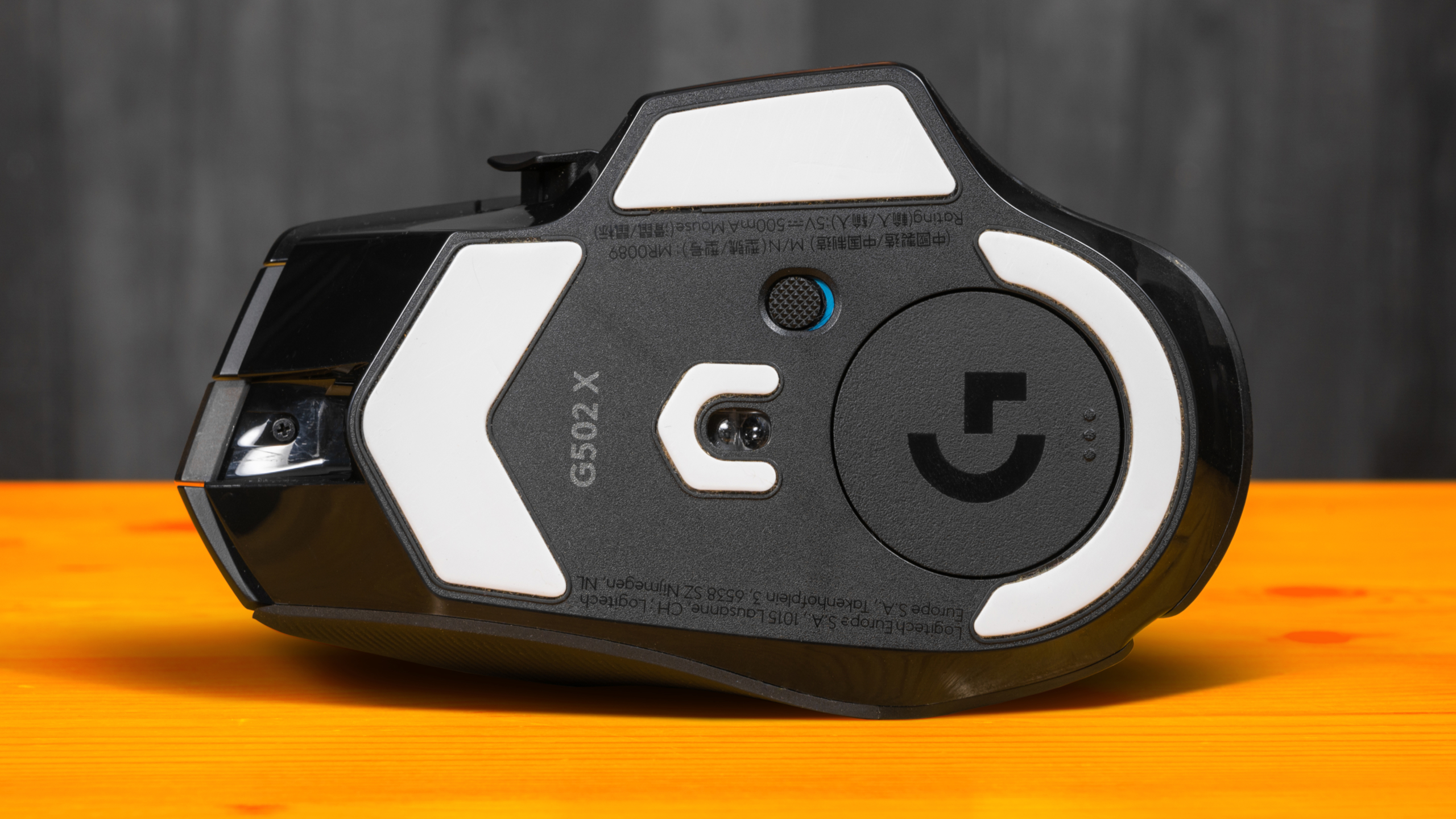 Onderaanzicht van de Logitech G502 X, met de Hero 25K-sensor en de teflon 'skates' duidelijk in beeld.