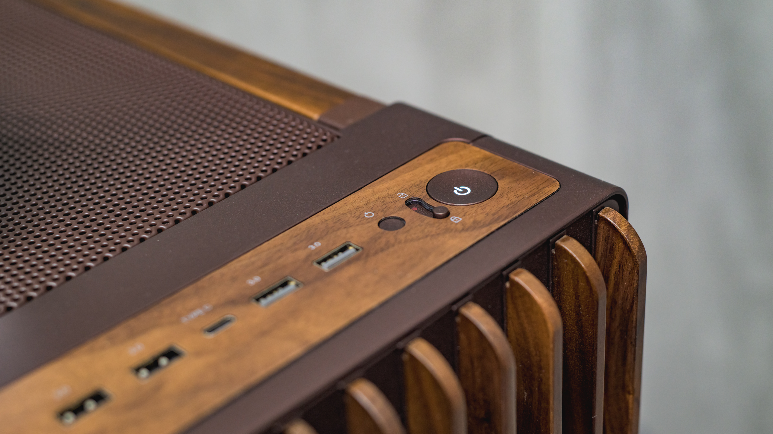 Close-up van de bruine ProArt PA602-behuizing, bij ASUS op IBC 2025. Naast de aan/uit-knop is duidelijk de vergrendeling daarvan zichtbaar; die moet ervoor zorgen dat de desktop niet per ongeluk uitgezet wordt tijdens lange rendertaken.