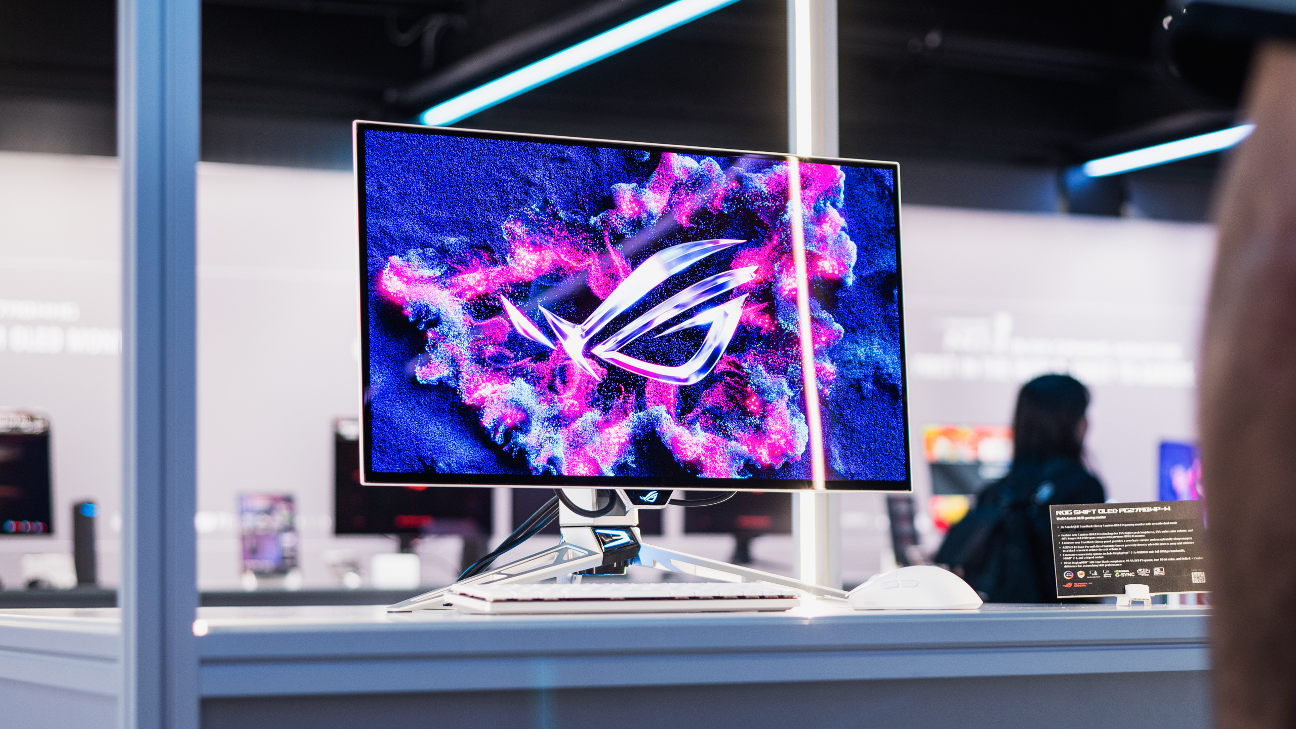 Vooraanzicht van de ASUS ROG Swift OLED PG27 AQWP-W-monitor, met daarop een kleurrijke Republic of Gamers-wallpaper.