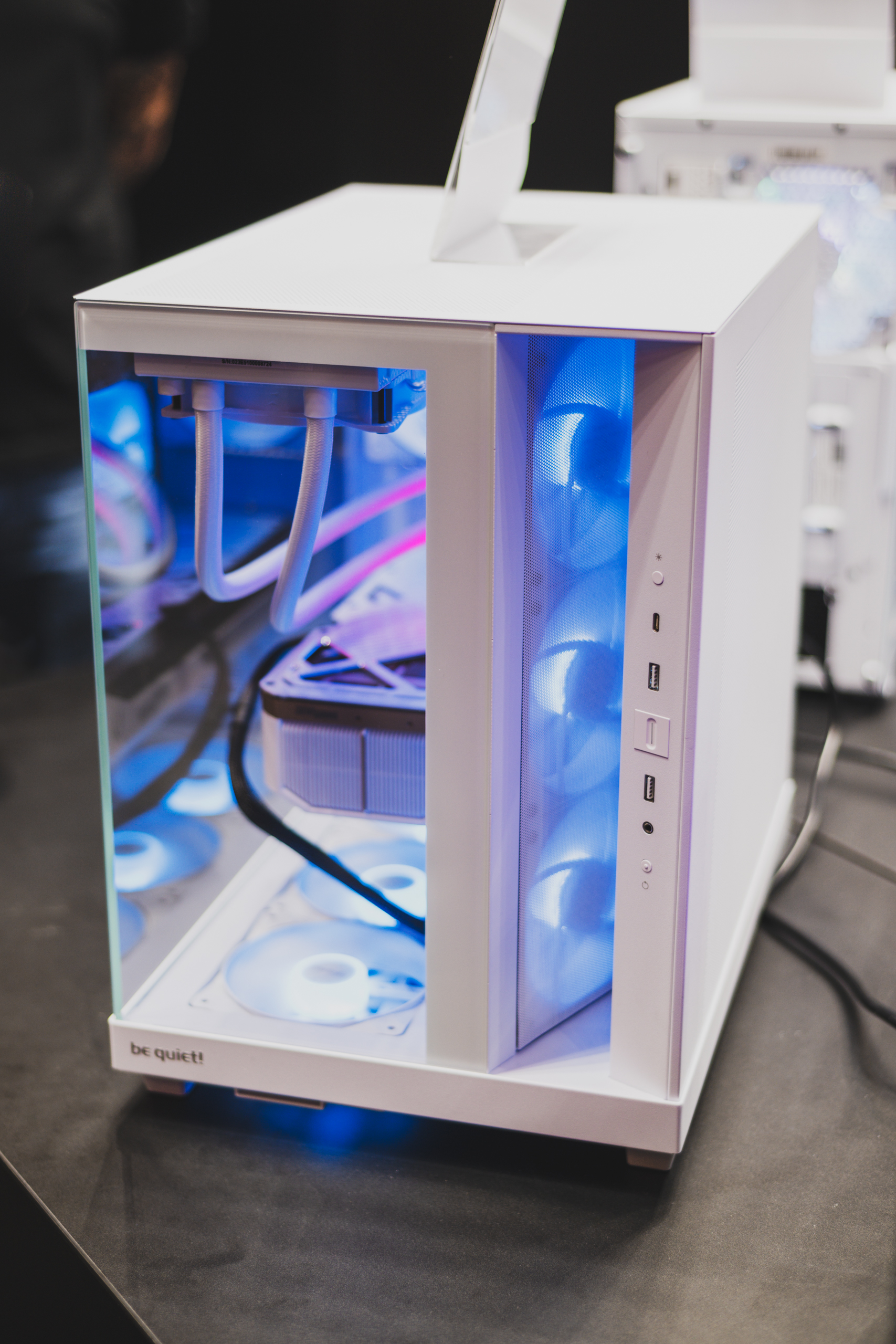 Vooraanzicht van de be quiet! Light Base 500 LX-behuizing in het wit. De twee glazen panelen zijn duidelijk zichtbaar, met aan de rechterflank het licht gekantelde ventilatorpaneel, hier paarsig blauw verlicht.