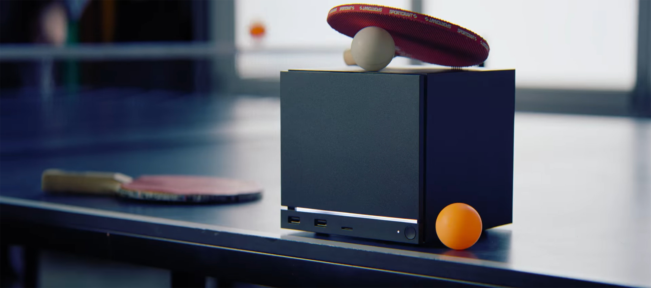 Lifestyle-foto van de Steam Machine, hier afgebeeld op een tafeltennistafel, inclusief batjes en balletjes.