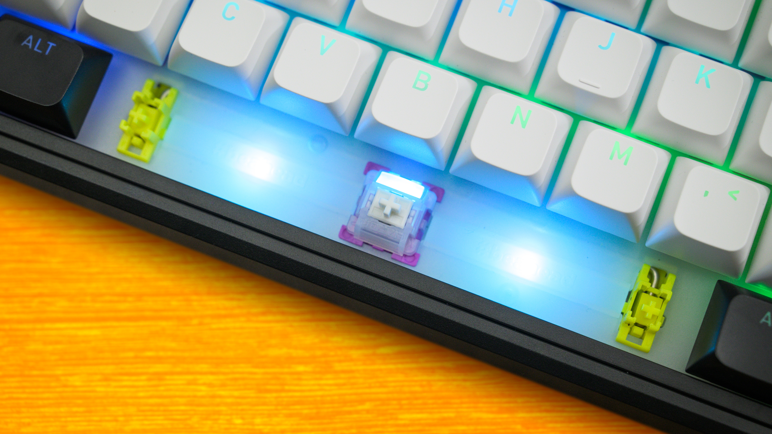 Close-up van de spatiebalk-schakelaar van de Hator Skyfall 80 MAG Ultima 8K, inclusief de twee omliggende RGB-lampjes en de gele stabilisatoren op de flanken.