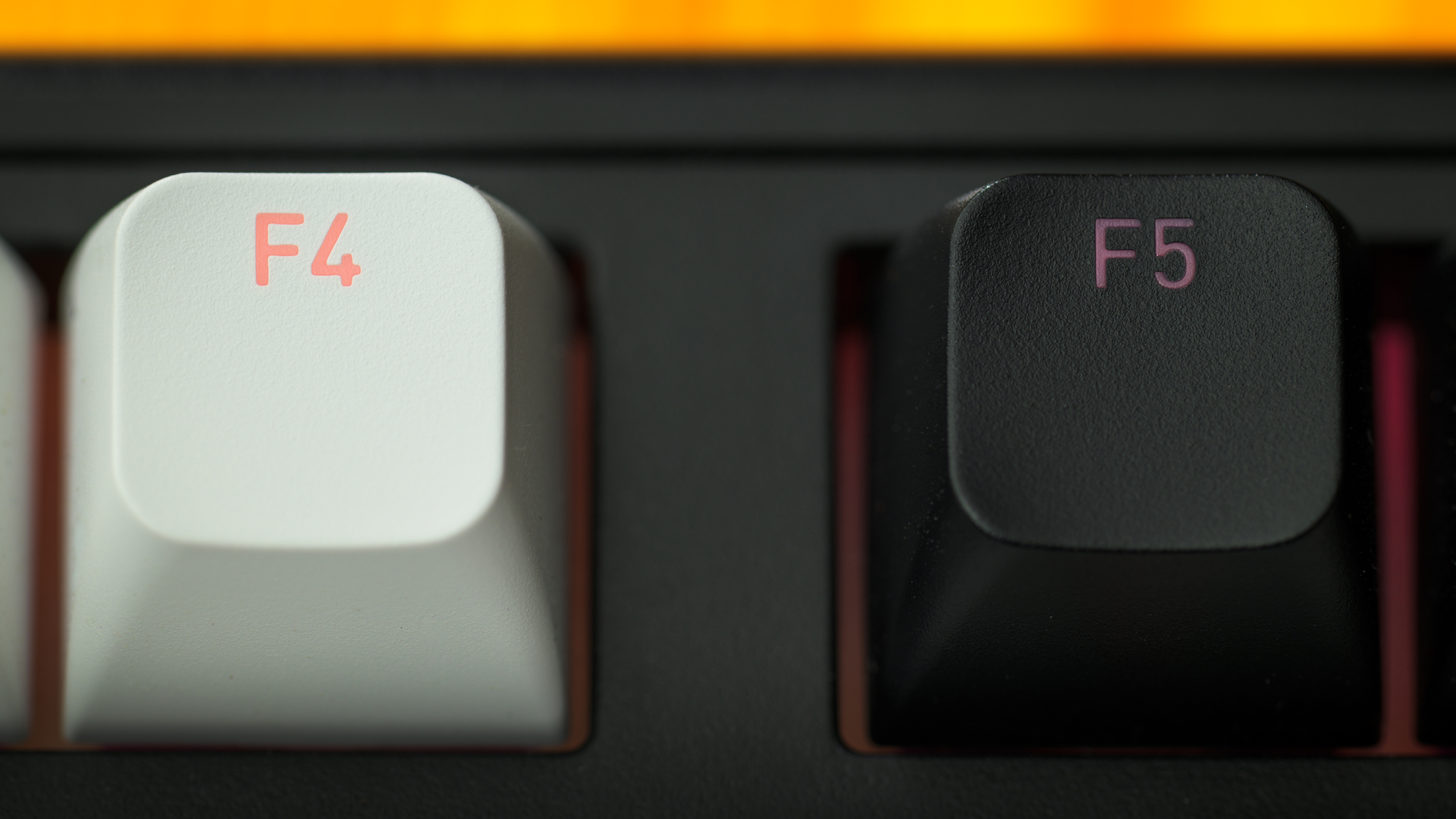 Close-up van zowel een witte als zwarte PBT-keycap op een Hator Skyfall 80-toetsenbord. Hier is duidelijk zichtbaar dat RGB-shinethrough beter te zien is in de witte keycaps dan de zwarte.